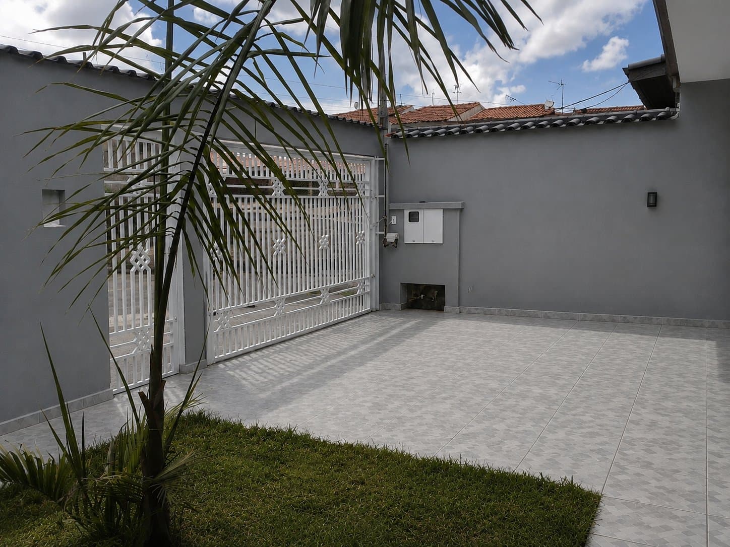 Quintal com jardim, palmeira e portão de entrada